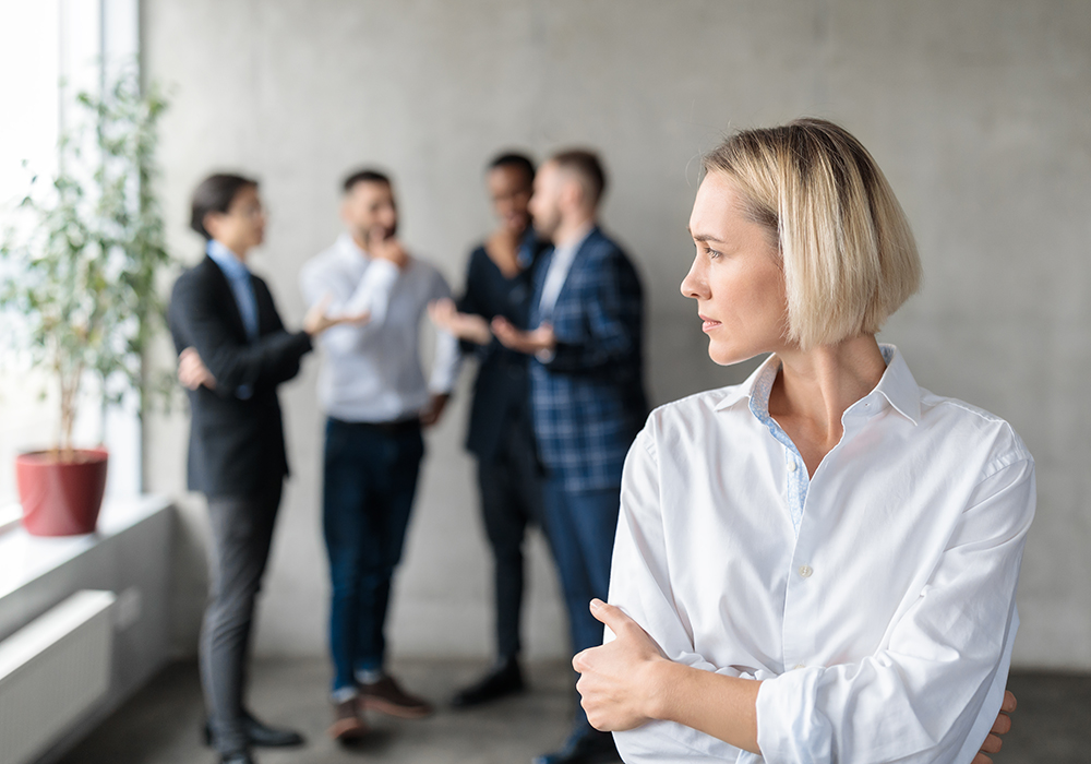 Une femme de face qui regarde un groupe d'homme entrain de parler dans son dos